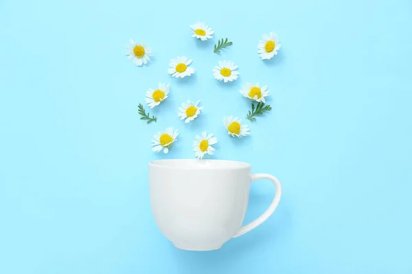 stock image Cup with chamomile flowers on blue background