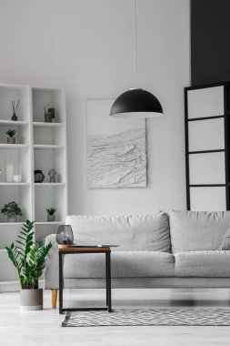 Işıl ışıl oturma odasının içinde rahat gri kanepe ve sehpanın üzerinde modern dizüstü bilgisayar.