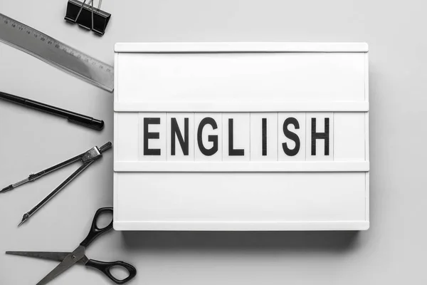 灰色の背景に単語英語と学校の文房具とボード — ストック写真