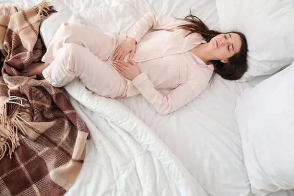Młoda Kobieta Cierpiąca Skurcze Menstruacyjne Sypialni Widok Góry — Zdjęcie stockowe