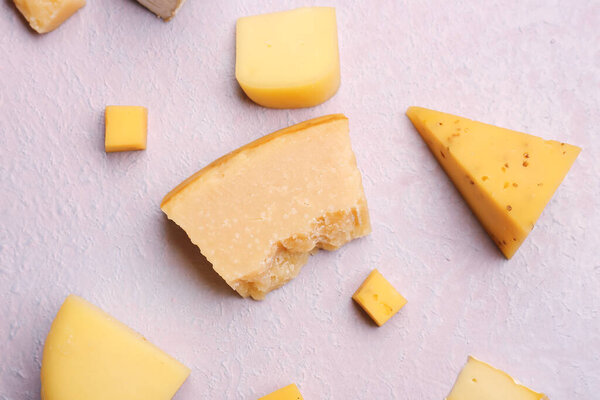 Pieces of tasty cheese on light background