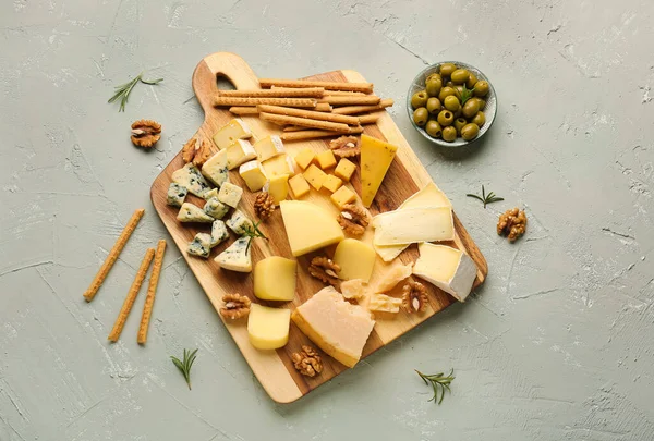 stock image Board with pieces of tasty cheese on light background