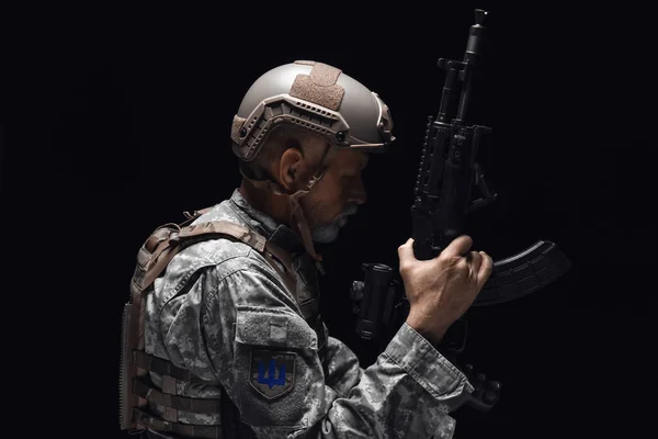 暗色の背景にアサルトライフルを持つ熟女兵士 — ストック写真