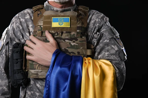 黒を背景にウクライナの旗を持つ熟女兵士 クローズアップ — ストック写真