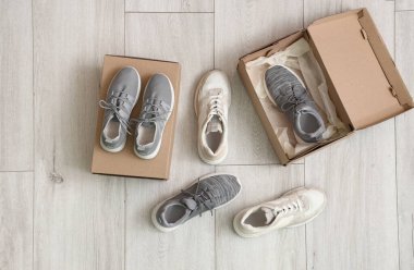 Açık ahşap arka planda farklı spor ayakkabıları olan karton kutular.