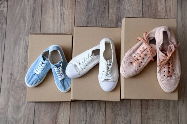 Hafif ahşap arka planda şık spor ayakkabıları olan karton kutular.