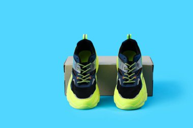 Mavi arka planda şık spor ayakkabıları olan karton kutu.