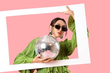 Güneş gözlüklü güzel bir kadın. Disko topu ve pembe arka planda çerçevesi var.