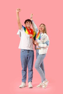 Pembe arka planda LGBT bayrakları olan mutlu genç bir çift.
