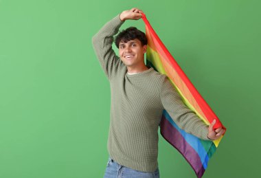 Yeşil arka planda LGBT bayrağı olan genç adam