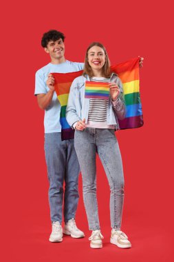 Kırmızı arka planda LGBT bayrakları olan genç bir çift