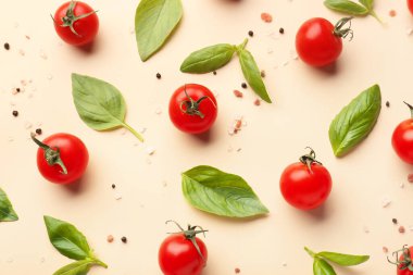 Olgun kiraz domatesleri, fesleğen yaprakları, deniz tuzu ve bej arka planda biber içeren kompozisyon