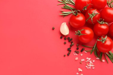 Kırmızı zemin üzerinde olgun kiraz domatesleri, biberiye, deniz tuzu ve biberli mısır kompozisyonu