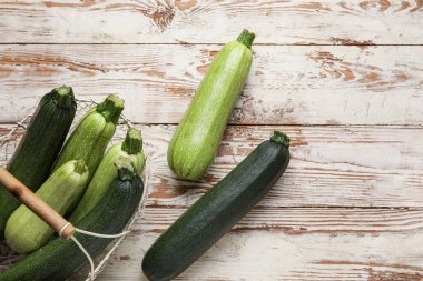 Beyaz ahşap arka planda yeşil kabaklı sepet.