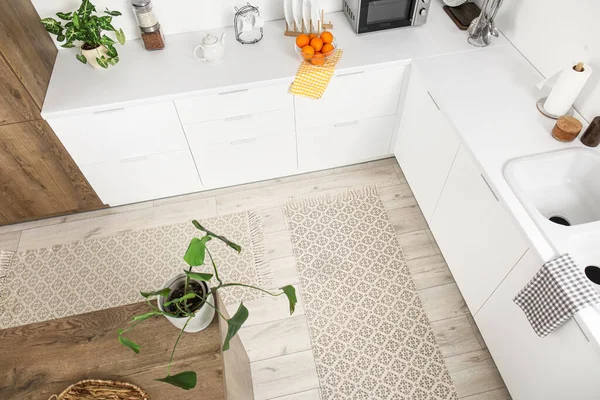 Stylish rugs on floor in light kitchen