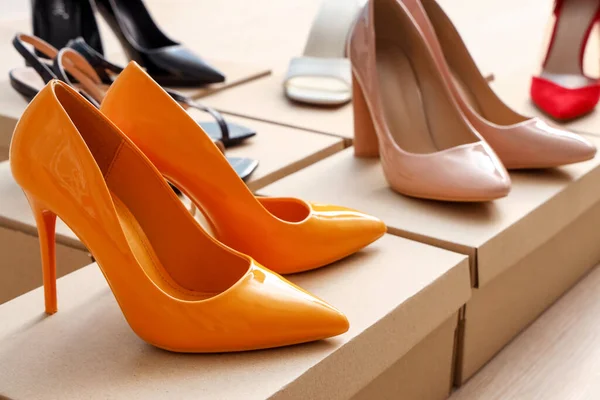 Cardboard boxes with high-heeled shoes on floor, closeup