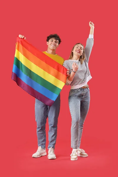 赤い背景にLgbtの旗を持つ幸せな若いカップル — ストック写真