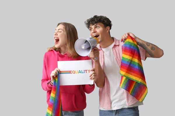 Lgbtの旗を持つ若いカップル 単語Equalityとメガホン光の背景に叫んで — ストック写真