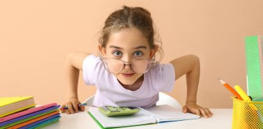 Masada bej arka planda ödev yapan zeki küçük kız.