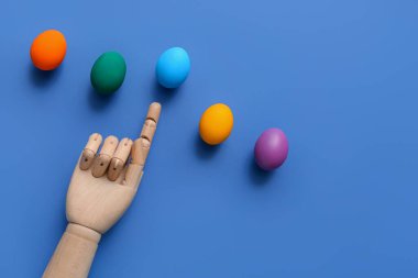 Süslü ahşap el ve mavi arka planda Paskalya yumurtaları.