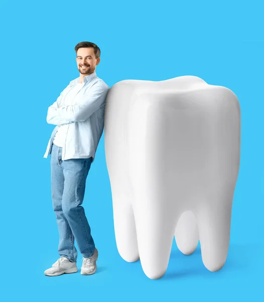 Happy man and big tooth on light blue background