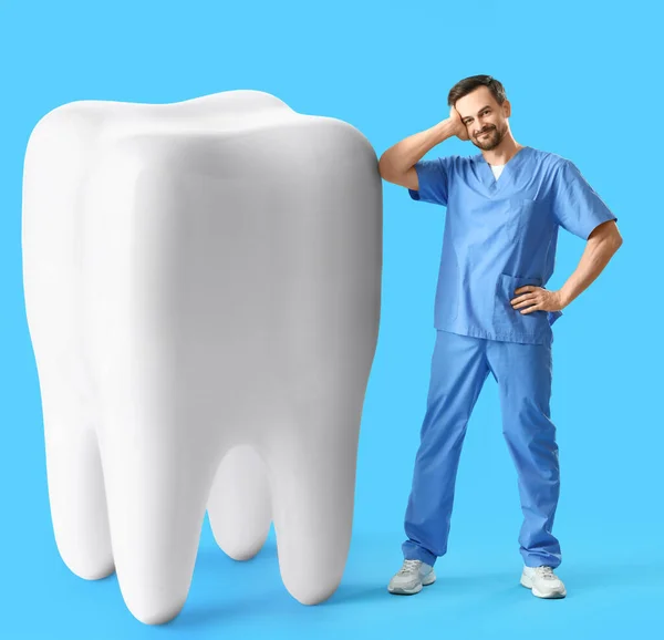 ライトブルーの背景に大きな歯を持つ男性歯科医 — ストック写真