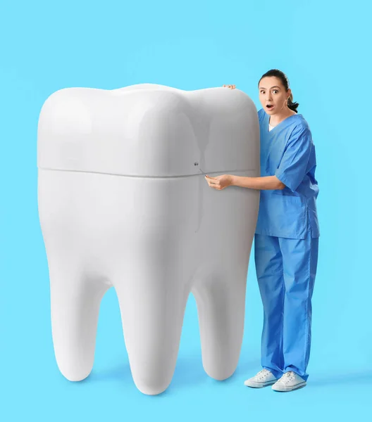 Überraschte Zahnärztin Mit Großem Zahn Auf Hellblauem Hintergrund — Stockfoto