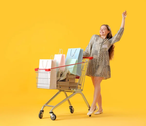 Gelukkig Vrouwelijke Verkoper Met Boodschappentassen Winkelwagentje Gele Achtergrond — Stockfoto