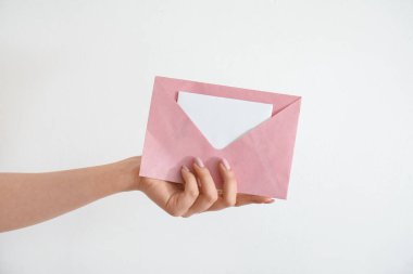 Beyaz arkaplanda boş davetiye olan bir zarf tutan kadın