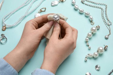 Renkli arka planda peçetesi olan şık bir yüzüğü cilalayan kadın, yakın plan.