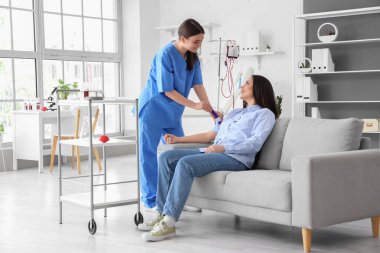 Kadın hemşire klinikte genç bir donörü kan nakline hazırlıyor.
