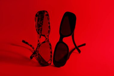 Kırmızı arkaplanda farklı stil güneş gözlükleri