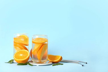 Mavi zemin üzerinde portakal dilimleri olan aşılanmış su bardakları.