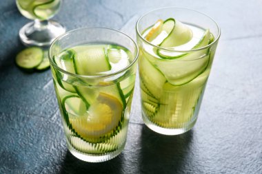 Koyu masada salatalık dilimleri ile doldurulmuş su bardakları.