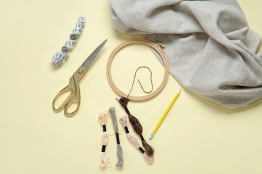 Soluk sarı arkaplanda tahta işlemeli çember, makas ve küflü iplikler.