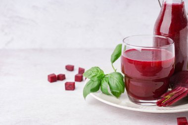 Hafif arka planda bir bardak taze pancar suyu.