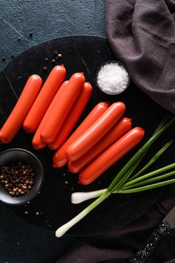 Lezzetli ince sosisli ve koyu arkaplanda yeşil soğanlı bir pano.