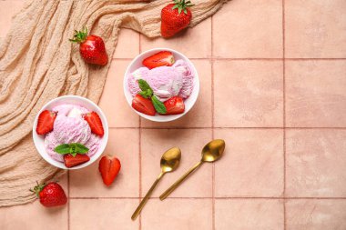 Böğürtlenli çilekli dondurma, nane ve altın kaşıklar bej fayans masasında.