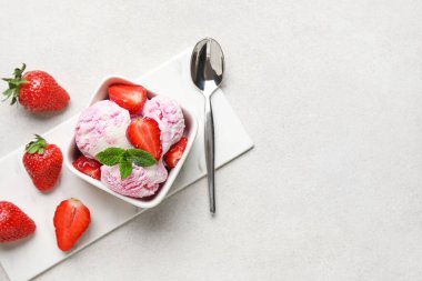 Nane, böğürtlen ve kaşıkla beyaz grunge masasında kare kase çilekli dondurma.