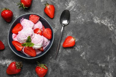 Gri grunge masasında çilekli dondurma, nane ve kaşık.