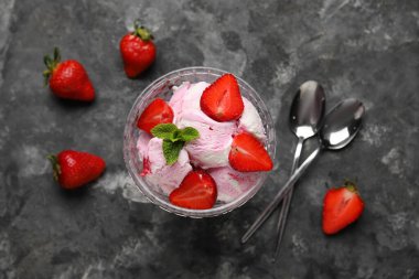 Bir kase çilekli dondurma, nane ve kaşıklar gri grunge masasında.