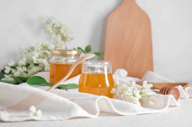 Arkaplanda akasya çiçekleri olan bal kavanozları