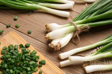 Ahşap zemin üzerinde taze taze soğan dilimleri olan tahta.