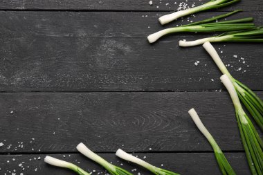 Siyah ahşap zemin üzerinde taze yeşil soğandan yapılmış çerçeve