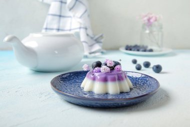 Böğürtlenli panna cotta tabakları ve beyaz masada güzel çigila çiçekleri.