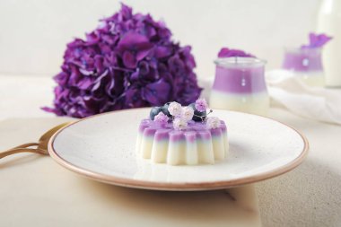 Beyaz masa üzerinde güzel ortanca çiçekleri olan bir tabak panna cotta.