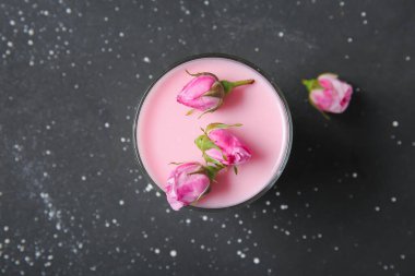 Bir bardak panna cotta ve siyah masanın üzerinde güzel pembe güller.