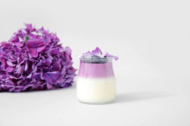 Bir bardak yaban mersinli panna cotta ve leylak arkaplanda güzel ortanca çiçekleri.
