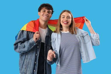 Mavi arka planda LGBT bayrağı olan genç çift