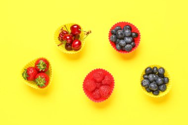 Sarı arka planda farklı taze meyveli kek kalıpları.